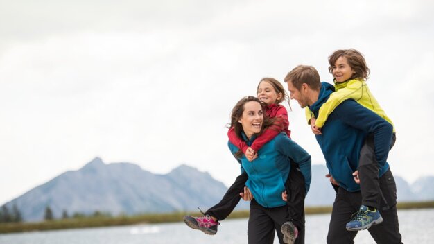 Laughing family of four at a lake in the Alps