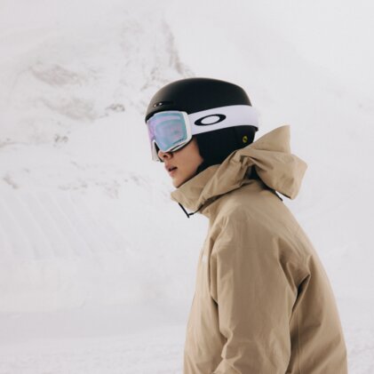 Eine Person in Snowboardausrüstung, einschließlich Helm, Jacke uns Skibrille, steht bereit für das Snowboarden im Schnee. | © 2026-10-15