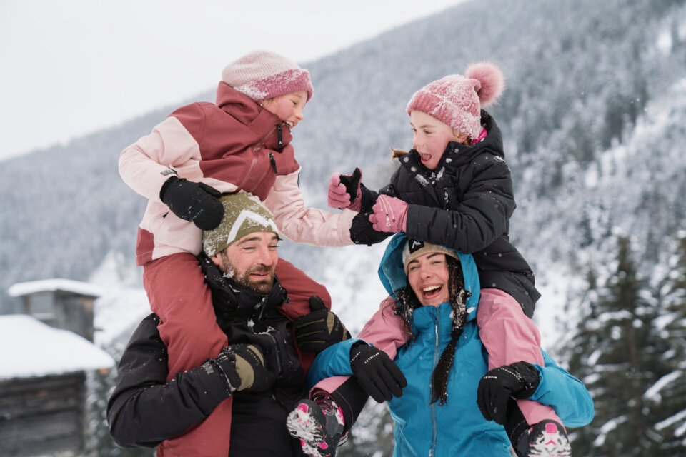 © INTERSPORT International Corporation GmbH A family is having fun in the snow with the parents giving their children piggyback rides. | © INTERSPORT International Corporation GmbH