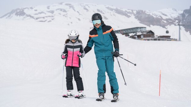 Vater hilft Tochter beim Skifahren. | © IIC/McKINLEY