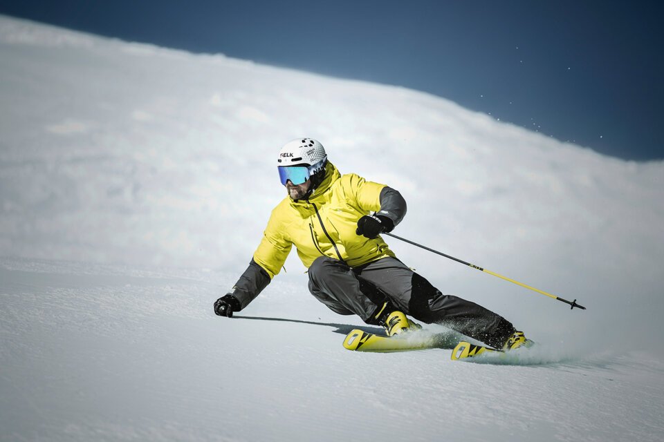 Skier in yellow jacket skiing down a snowy slope. | © Fischer Sports GmbH