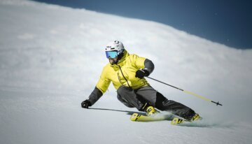 Skier in yellow jacket skiing down a snowy slope. | © Fischer Sports GmbH