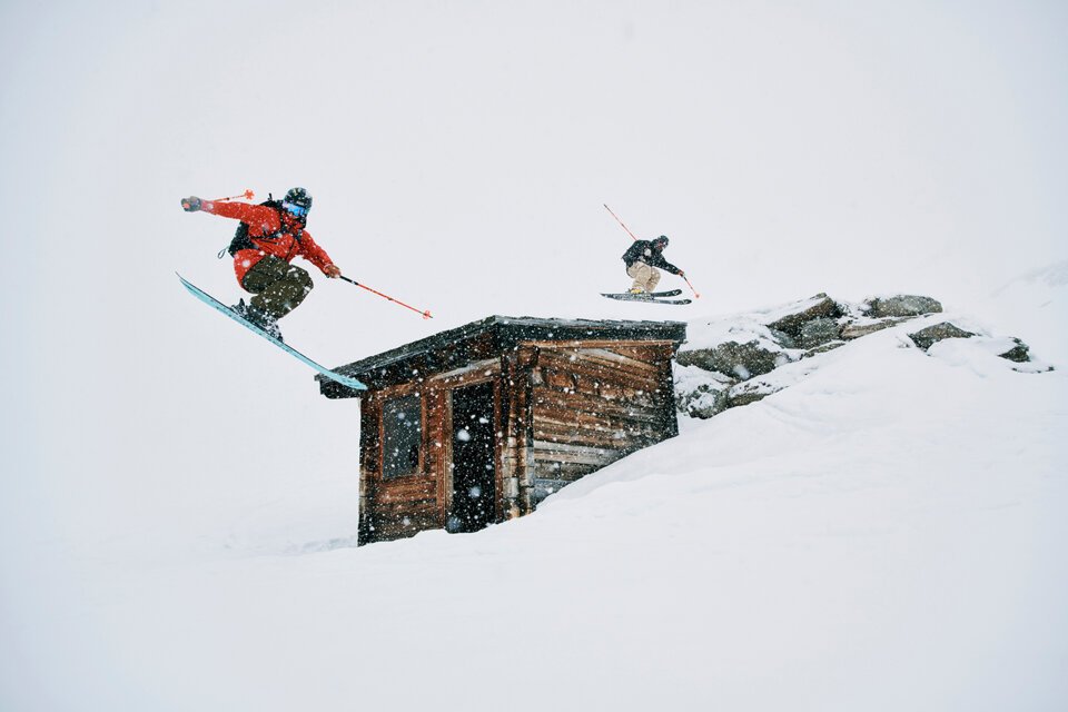 Zwei Skifahrer springen über ein Gebäude im Schnee. | © Fischer Sports GmbH