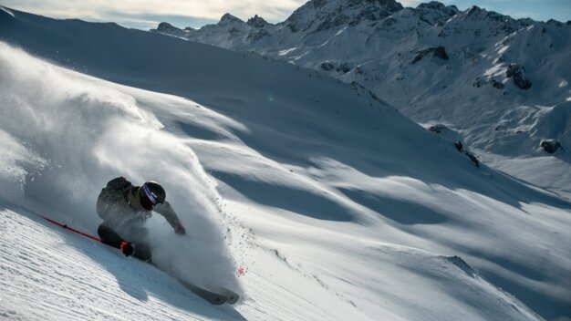 Skier carving through powder with mountains in background | © Fischer Sports GmbH