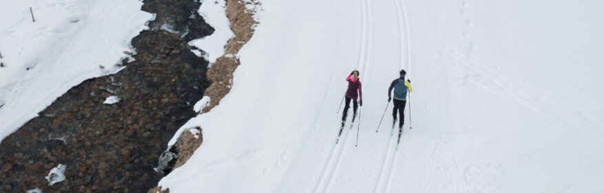 Zwei Skilangläufer neben einem Fluss in verschneiter Landschaft. | © INTERSPORT International Corporation GmbH