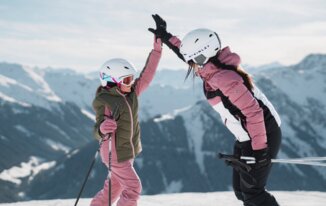 © INTERSPORT International Corporation GmbH Zwei Skifahrerinnen geben sich ein High-Five vor einer Bergkulisse. | © INTERSPORT International Corporation GmbH