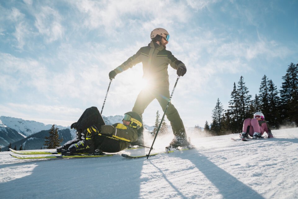 Skifahrer stürzt und wird von anderem Skifahrer überquert, während ein Kind im Hintergrund sitzt. | © INTERSPORT International Corporation GmbH