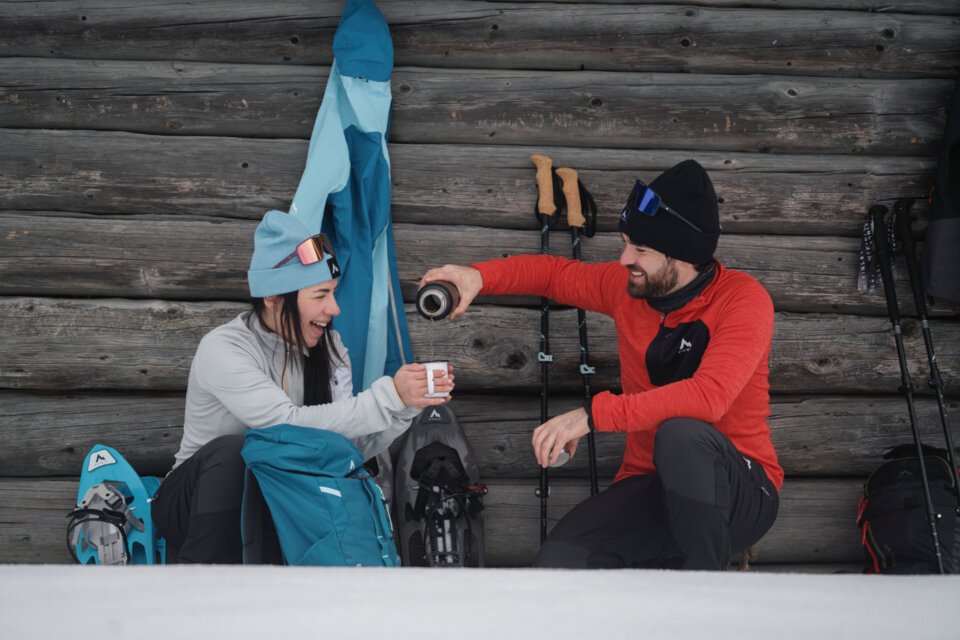 © INTERSPORT International Corporation GmbH Zwei Personen machen eine Pause beim Schneeschuhwandern und trinken Kaffee. | © INTERSPORT International Corporation GmbH