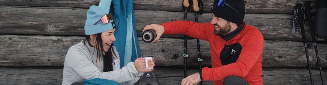 Zwei Personen machen eine Pause beim Schneeschuhwandern und trinken Kaffee. | © INTERSPORT International Corporation GmbH
