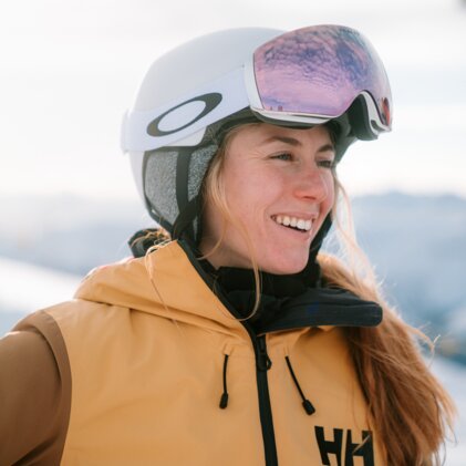 Woman smiling wearing ski helmet and goggles.