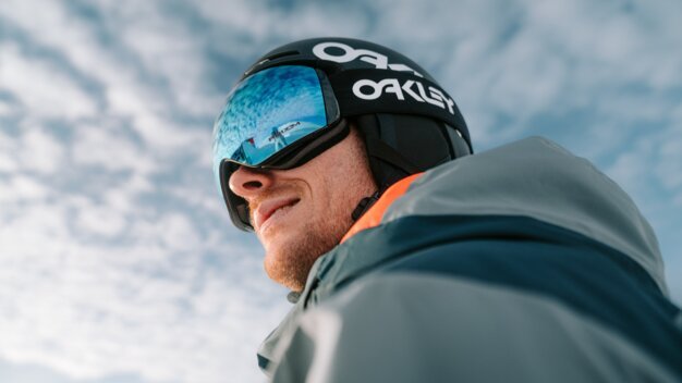 Skier wearing Oakley helmet and goggles looking off into the distance.