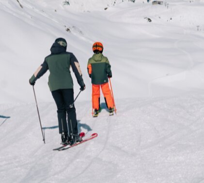 Vier Personen fahren Ski auf einer Skipiste.