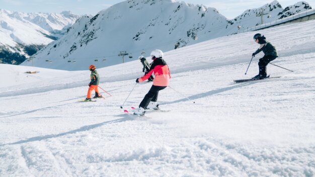 Skifahrer auf einer verschneiten Piste mit Bergen im Hintergrund
