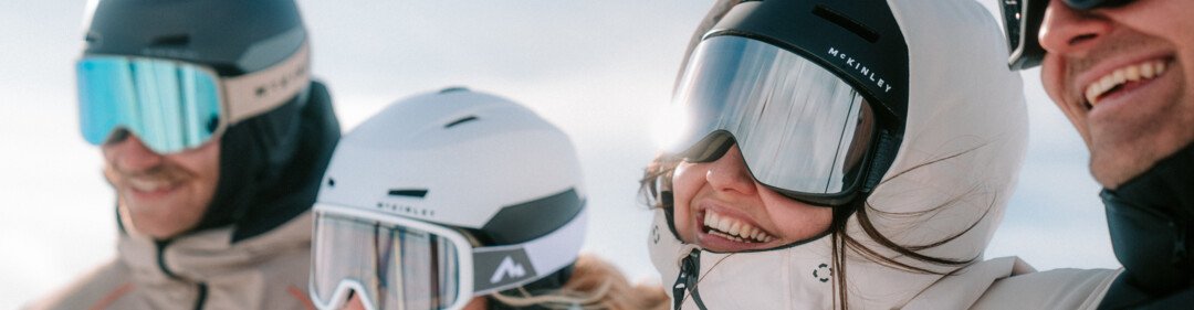 Gruppe von vier Personen mit Skihelmen und Skibrillen lächelt.