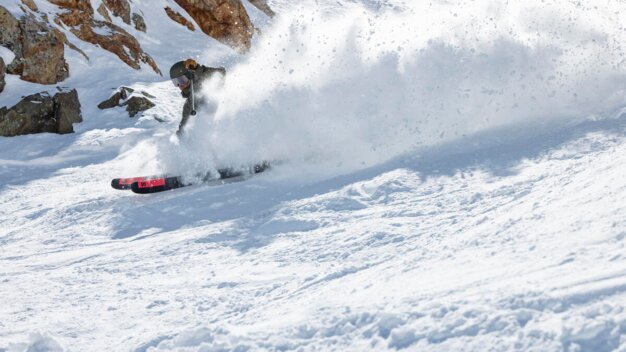 Skier riding through powder with snow spraying up.
