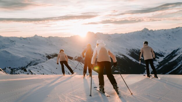 Gruppe von Skifahrern bei Sonnenuntergang in den Bergen.