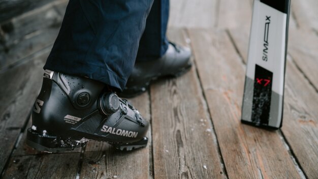 Skischuh der Marke Salomon mit einem Ski im Hintergrund.