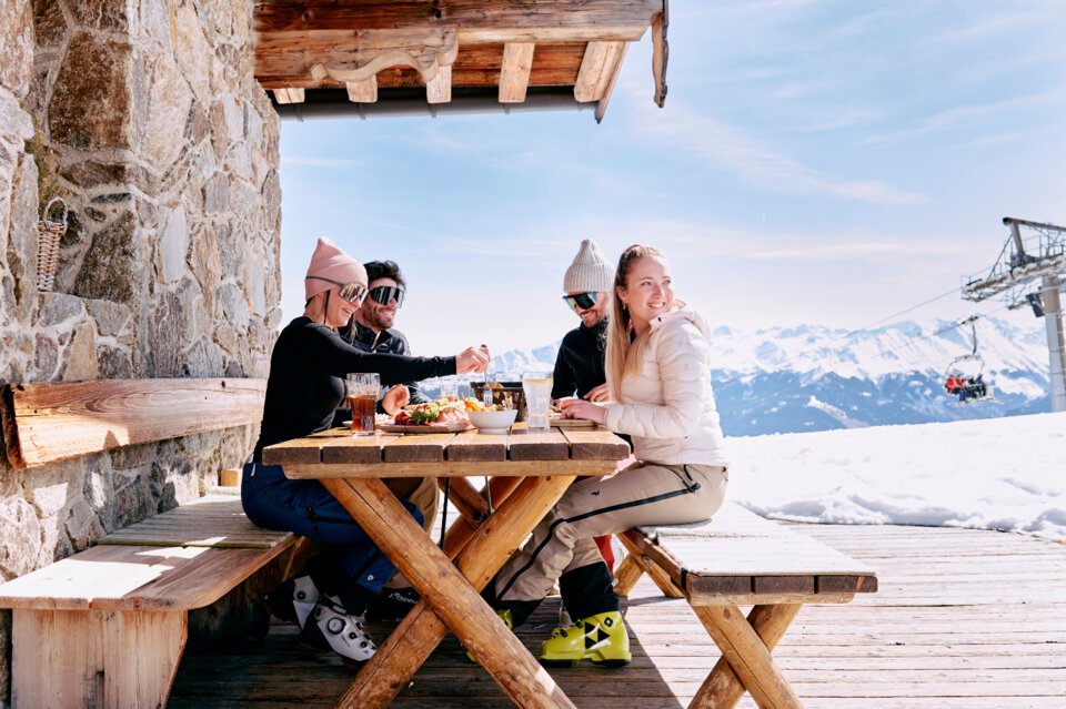 © ARMIN WALCHER Group of skiers eating at an outdoor table. | © ARMIN WALCHER