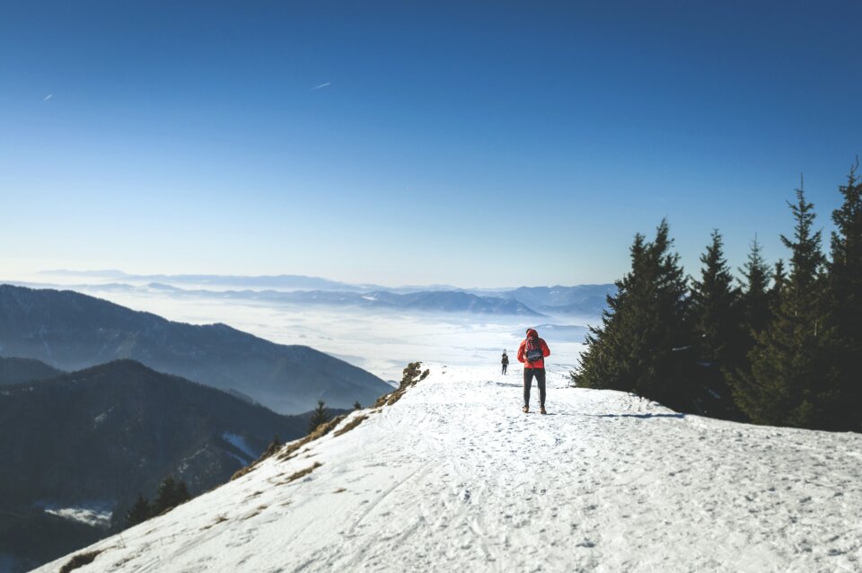Zwei Wanderer im Schnee auf einem Berggipfel.