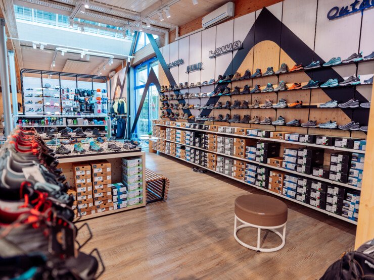 Sales area of an INTERSPORT Rent shop with a wide selection of running and outdoor shoes on display walls