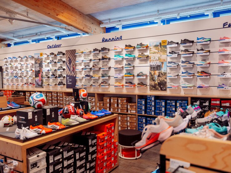 Retail section of an INTERSPORT Rent shop with a wide selection of running and casual footwear and accessories