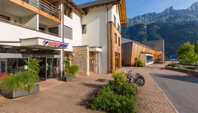 Intersport store with bicycles parked outside and mountains in the background