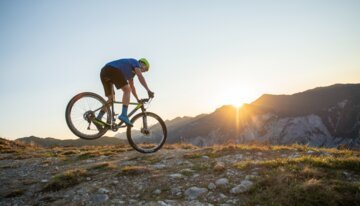 Mountainbiker auf Hardtail bei Sonnenuntergang