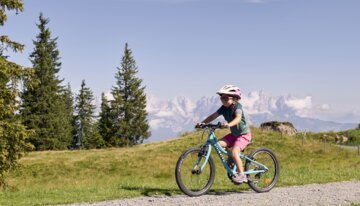 Mädchen fährt mit dem Fahrrad auf einem Bergpfad.